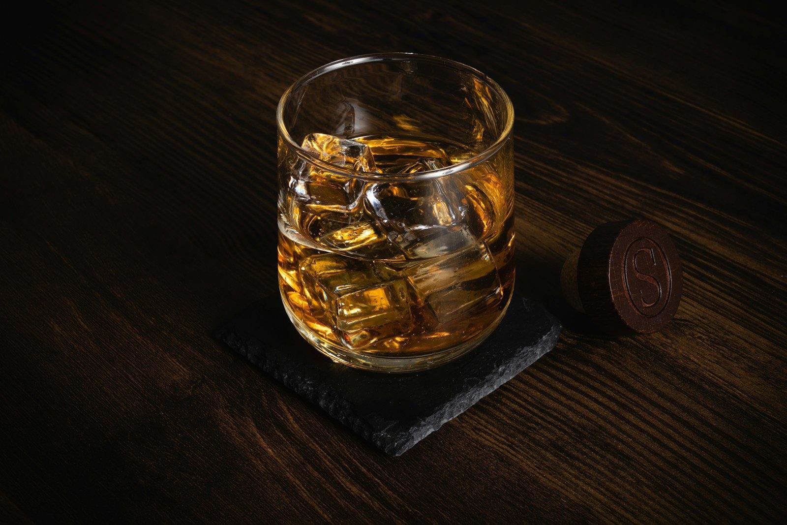 A crystal whisky tumbler sitting on a wooden table, showcasing the classic "rocks glass" style.