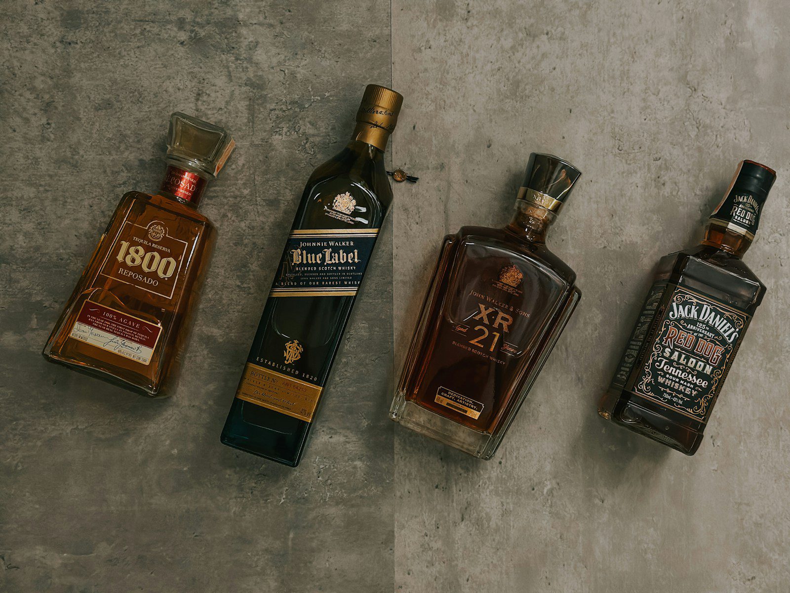 Different types of whiskey bottles including Scotch, Bourbon, and Rye on a rustic wooden bar