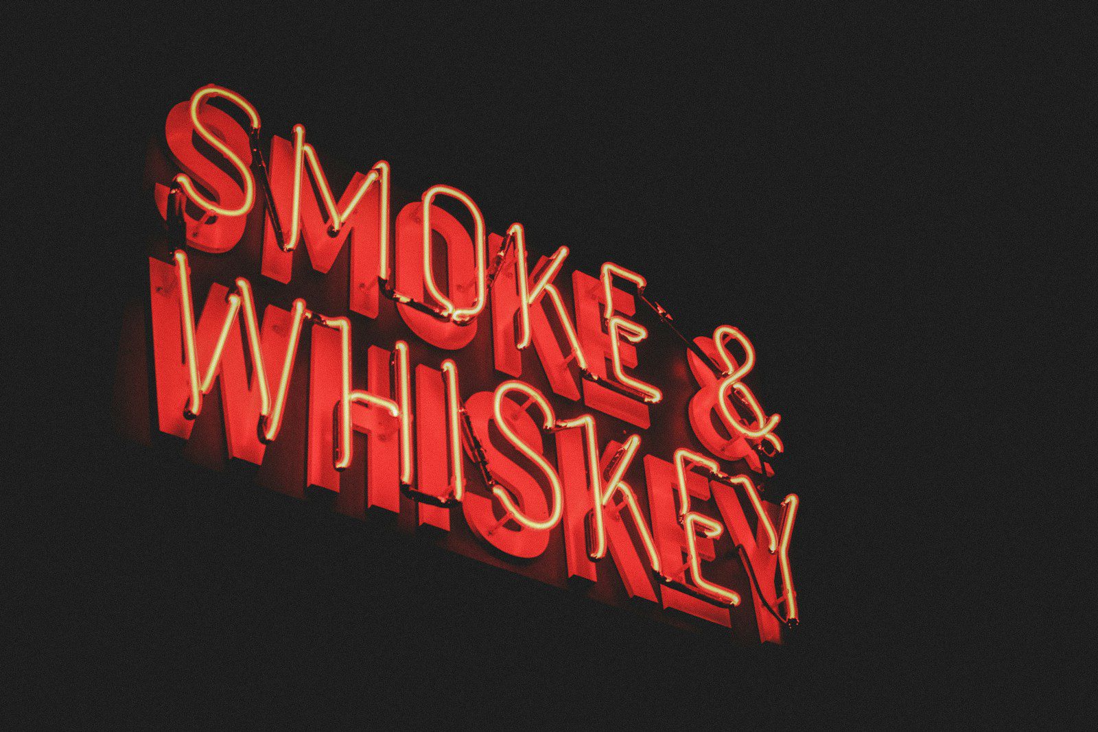 A glass of lightly peated whisky with gentle smoke rising next to a bottle